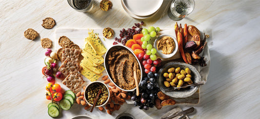 A vegan charcuterie board featuring grapes, olives, nuts, dried fruit, a homemade vegan pate and homemade vegan cheese, and toast