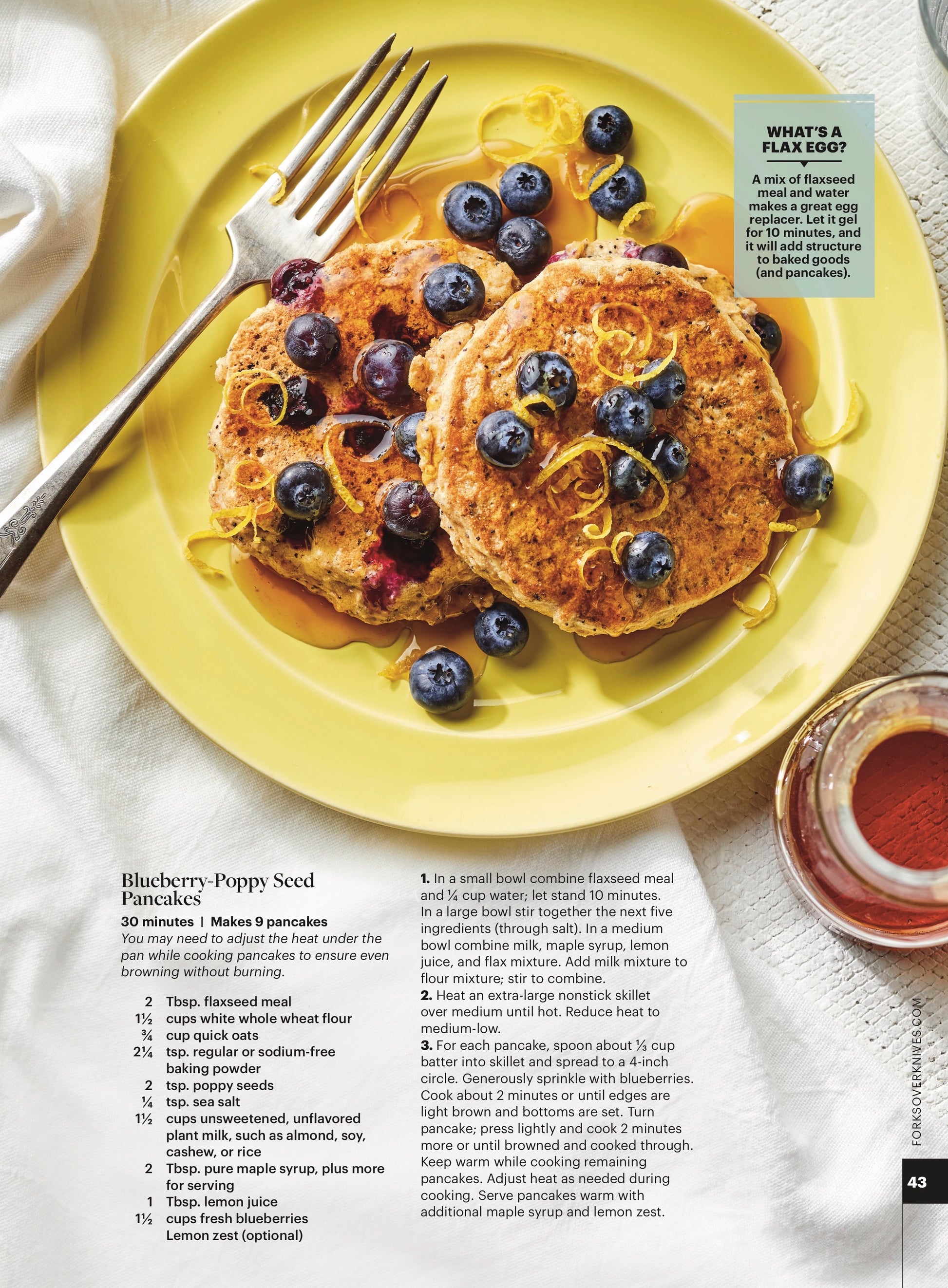 Blueberry-Poppy Seed Pancakes on a bright yellow pate with a fork and a small bowl of maple syrup